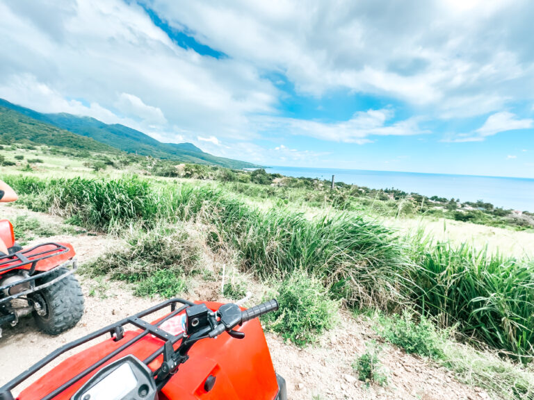 Red all terrain vehicles are parked on a Basseterre, St. Kitt's hillside overlooking the ocean