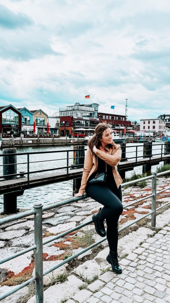 A woman stands in front of the Alter Strom Canal in Warnemunde, Germany.